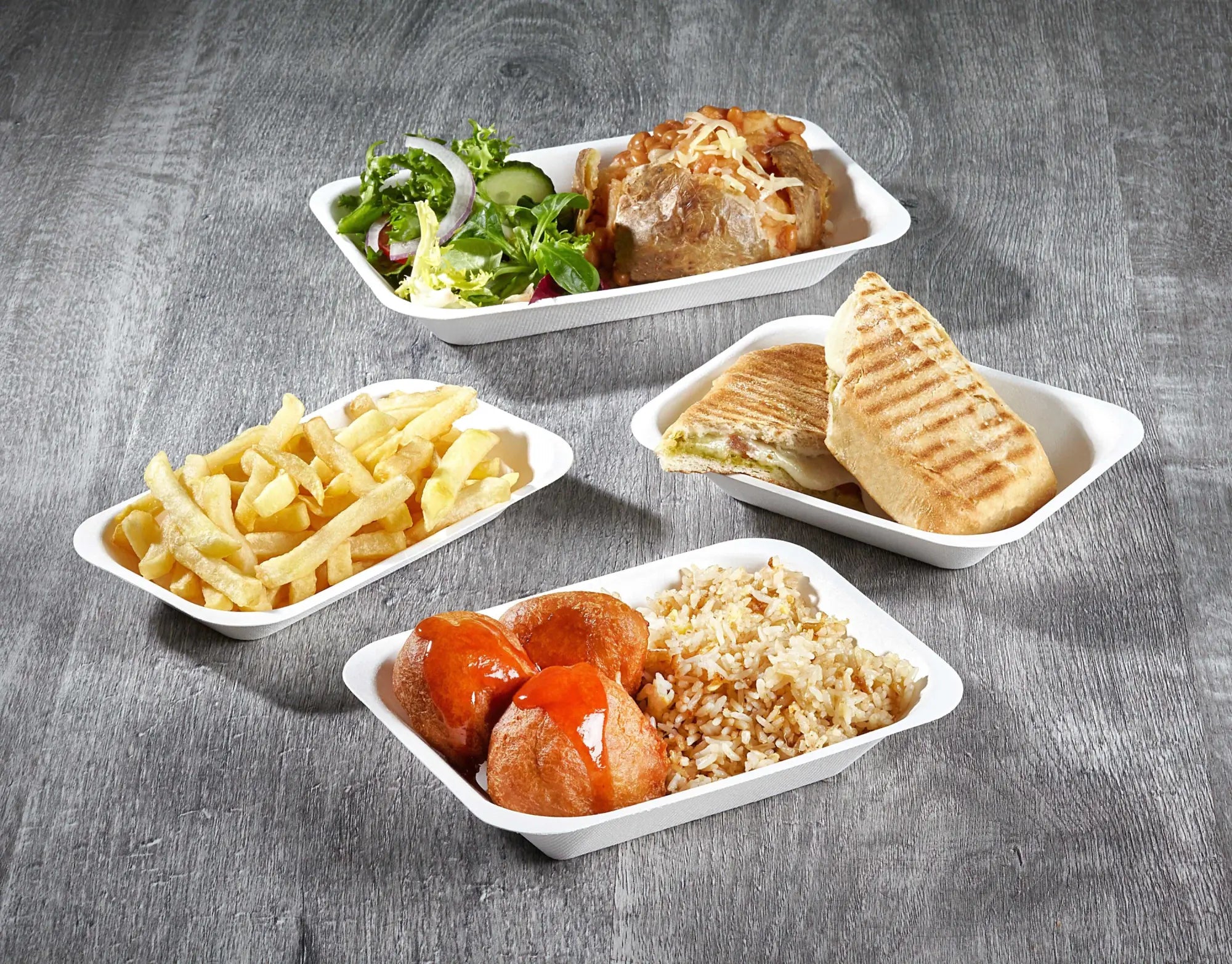Assortment of biodegradable eco food dishes on white plates showcasing eco food packaging solutions