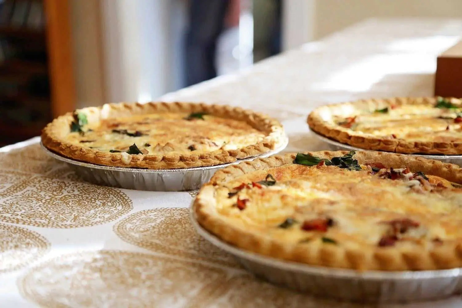 Freshly baked foil pie dishes with golden crusts on a table in Foil Trays & Foil Pie Dishes collection