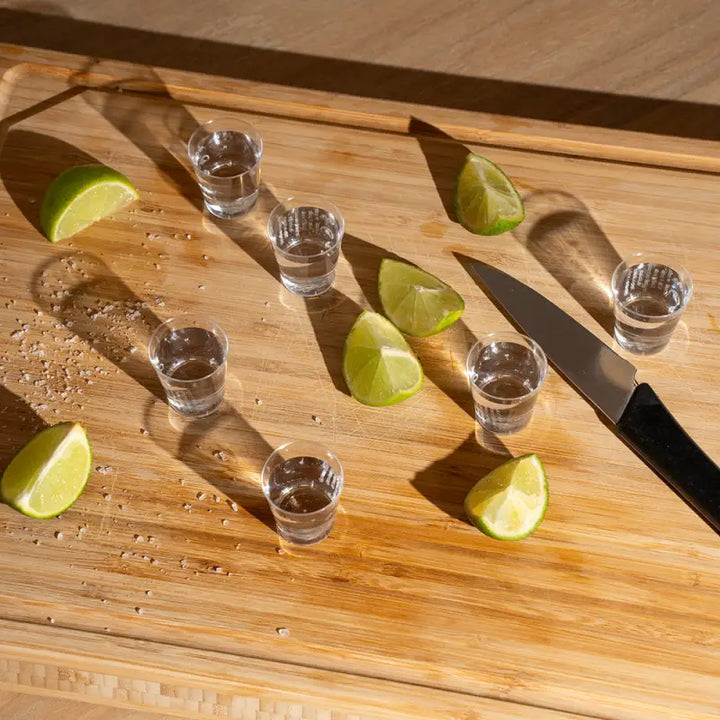 Plastic shot glasses with tequila shots and lime wedges for party servings