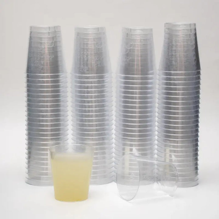 Stacks of clear 2cl plastic shot glasses with lined markings for accurate serving