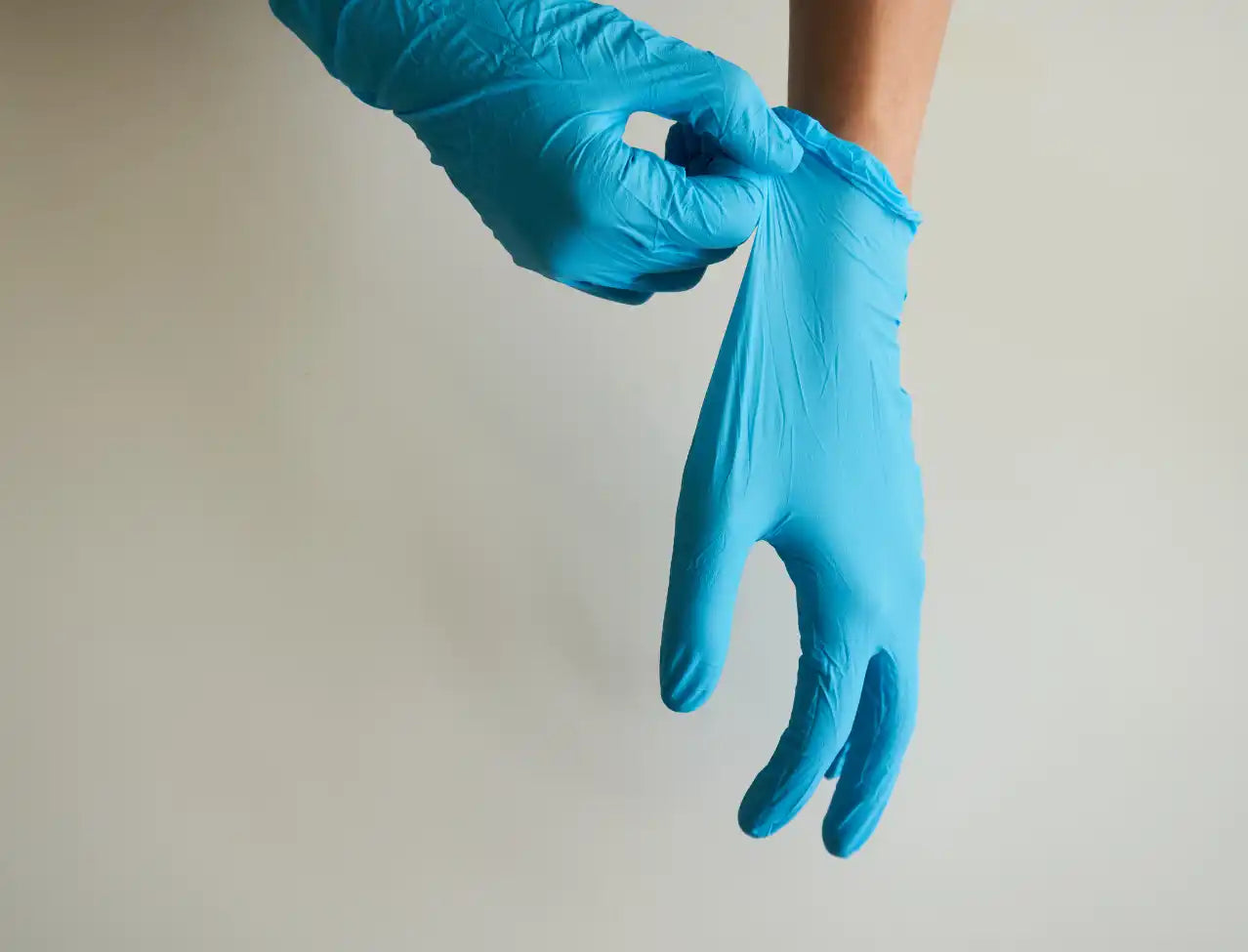 Blue nitrile medical glove being put on a hand.