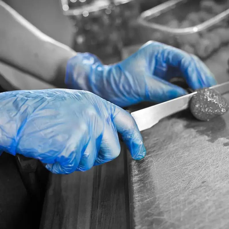 Hands in blue latex gloves holding a knife with Blue Vinyl Powder Free Disposable Glove