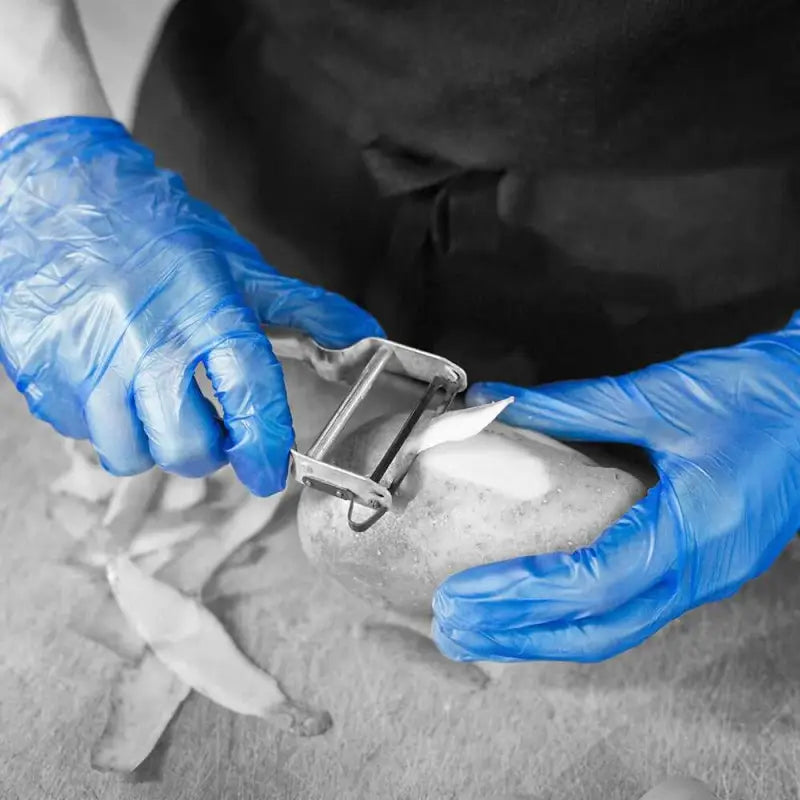 Potato peeler held by hands in blue vinyl powder free disposable gloves Shield GD13