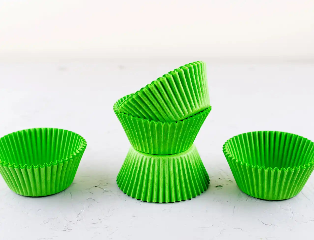 Bright lime-green paper cupcake liners stacked and arranged on a surface.