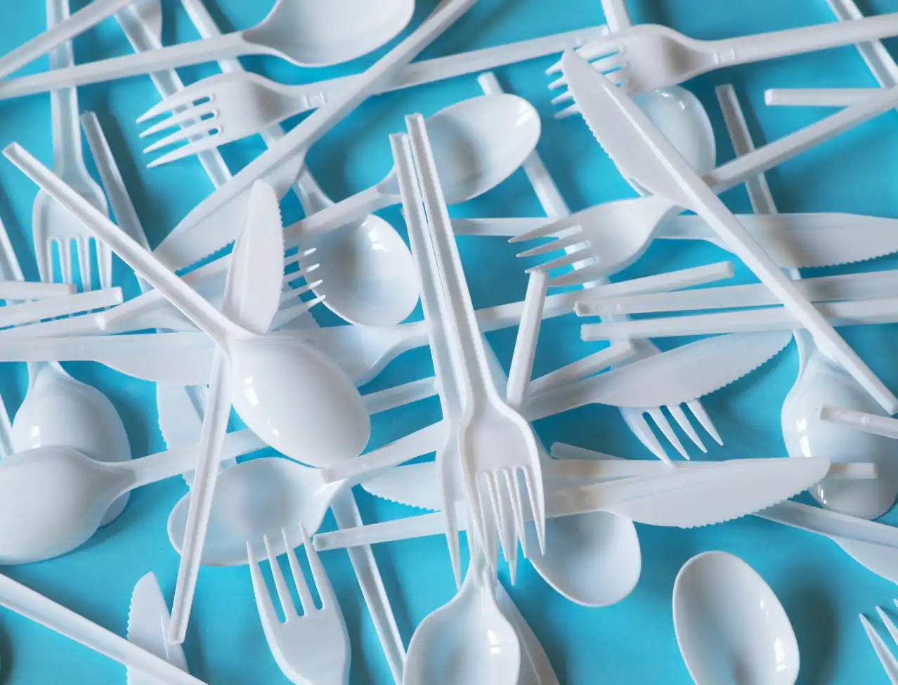 White plastic disposable utensils scattered across a surface.