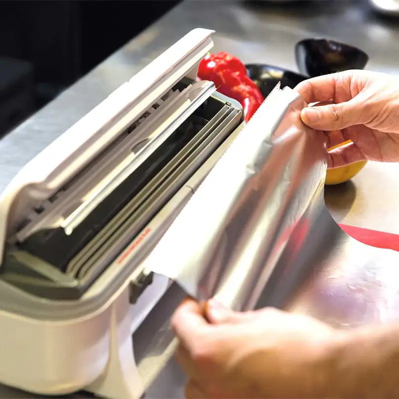 Knife sharpener honing a kitchen knife next to Wrapmaster 3000 Aluminium Foil 24C54