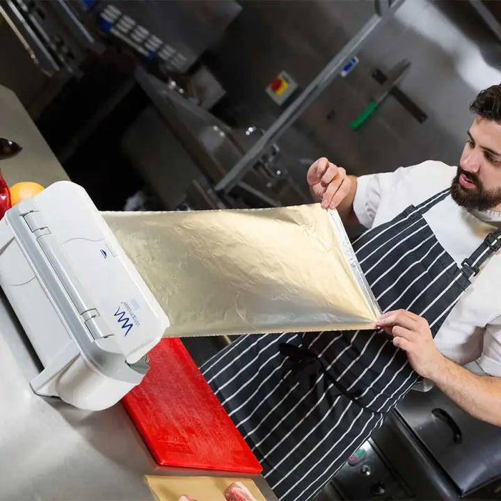 Chef in striped apron stretches pasta dough with Wrapmaster 3000 Dispenser - 63M98