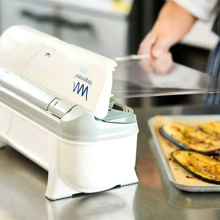 Food wrap dispenser with plastic wrap being pulled from Wrapmaster 3000 Dispenser - 63M98