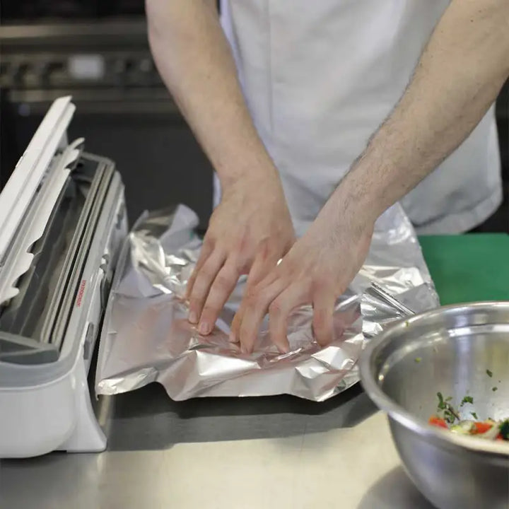 Hands using Aluminium Foil 24C55 to wrap food on a kitchen counter with Wrapmaster 4500