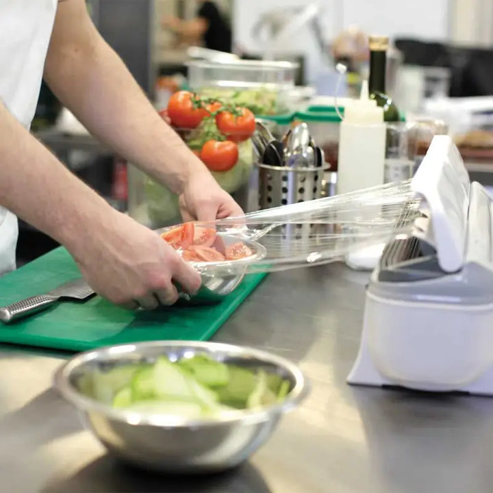 Hands preparing food on a kitchen counter with Wrapmaster 4500 Dispenser - 63M97 and baking parchment
